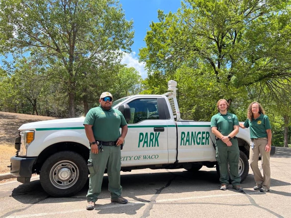 Three Park Rangers stand next to a Park Ranger truck
