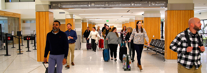 happy passengers walking through the airport with their luggage.