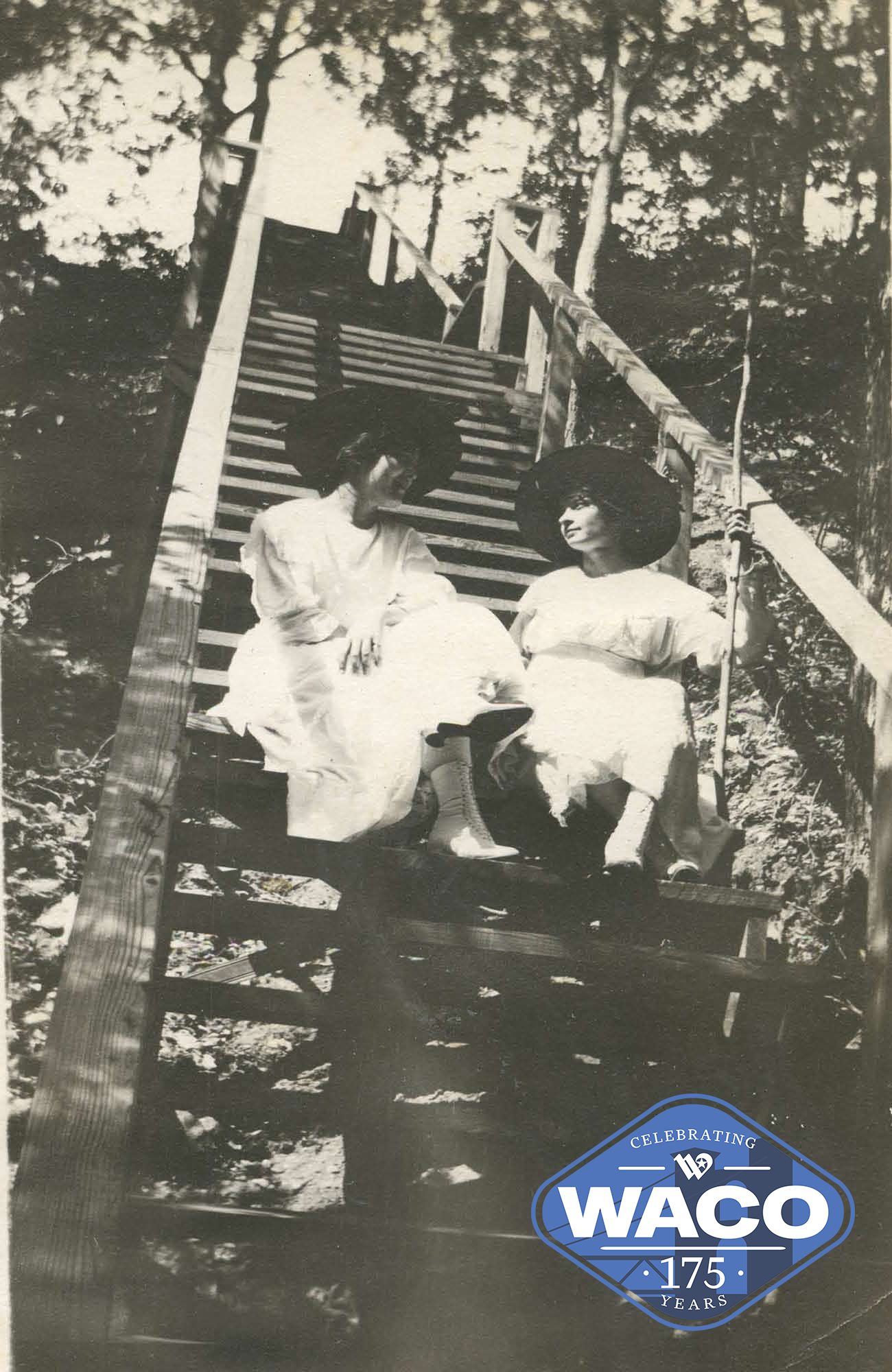 Black and white photo of two young women sitting on steep stairs on a cliff