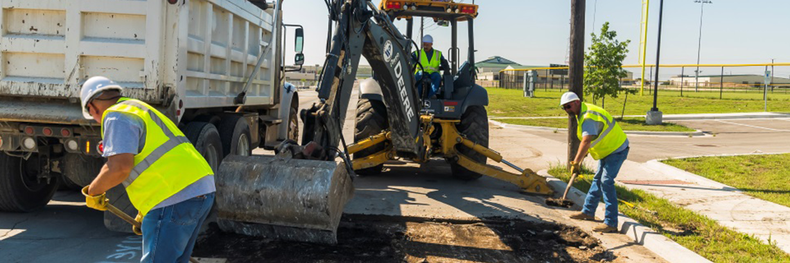 Three Public Works employees working on repairing a road