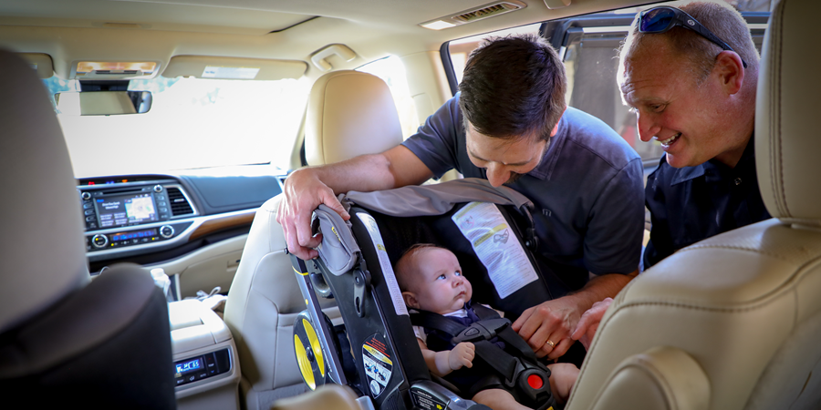 Firefighter and a dad looking at a baby in a car seat
