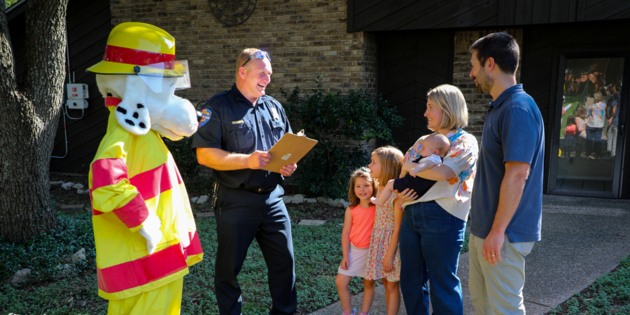 Firefighter and Sparky the fire dog talking to a family outside a home