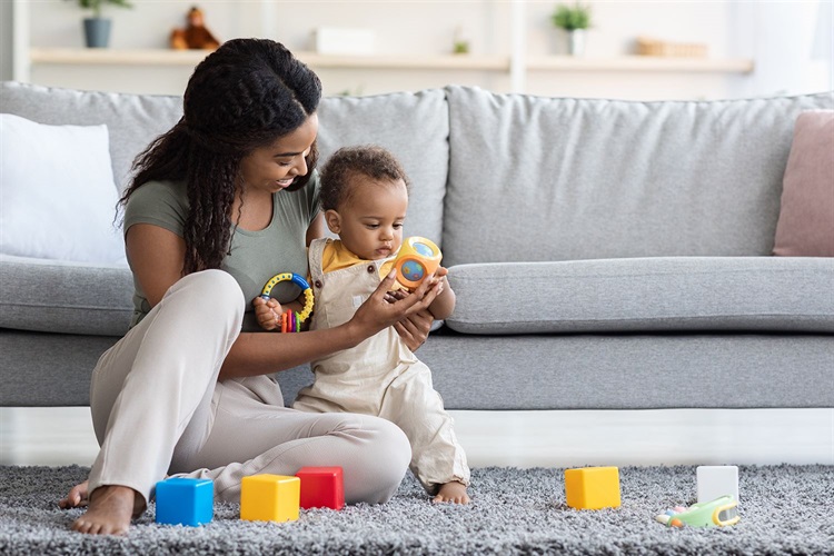 Picture of African American mom and baby sitting on the floor playing with toys.