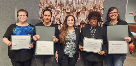 Group picture of four Health360 program graduates with their lifestyle coach holding diplomas at their graduation on January 3, 2023.
