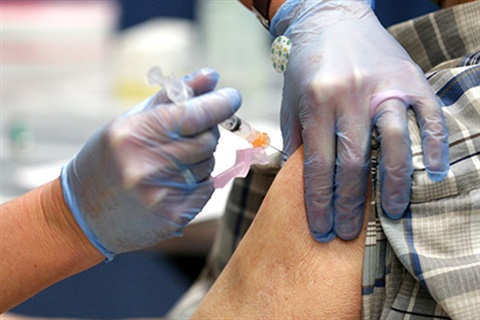 Medical person wearing gloves giving a vaccine to someone.