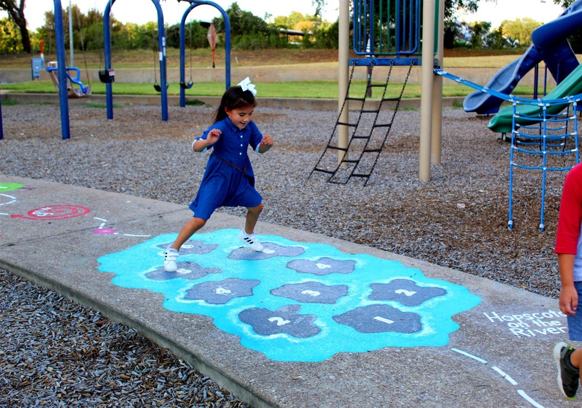 Photo of girl playing on a sidewalk chalk obstacle course at Bledsoe-Miller Park.