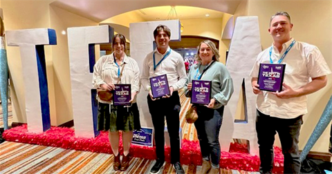 Two women and two men holding up awards in front of large TFEA letters