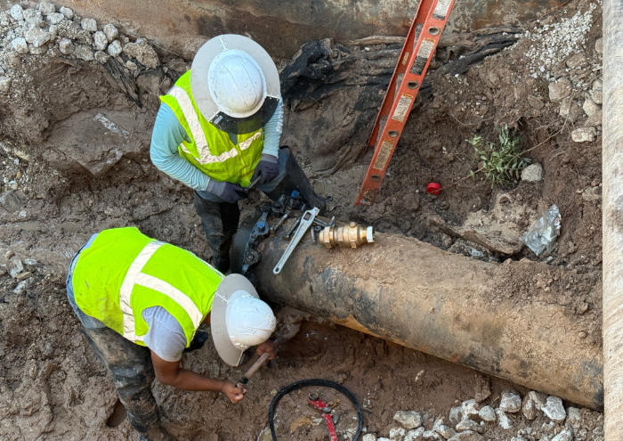 two staff members repair a water main