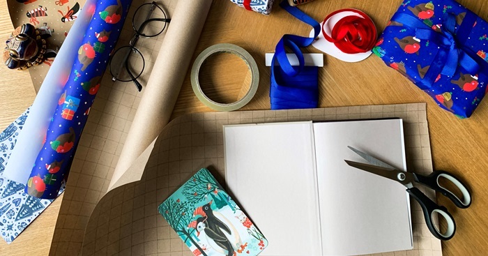 A table with wrapping paper, ribbon, tape, and scissors