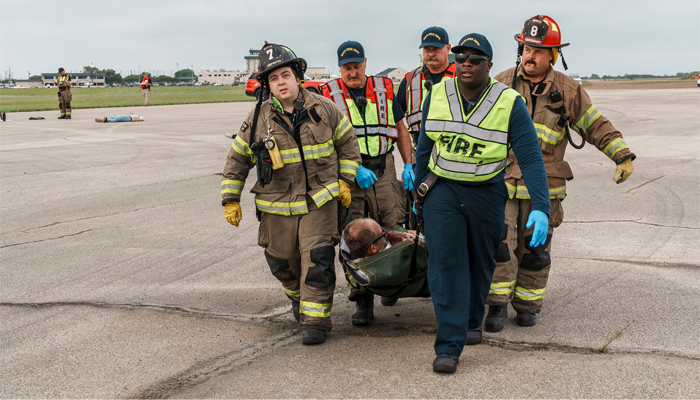 Firefighters pulling volunteer on an airport tarmac