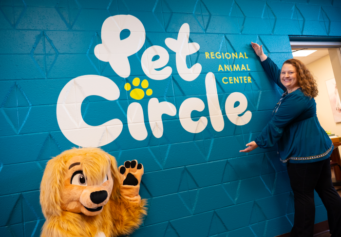 Melissa Sheldon and Chance the dog mascot showing off a Pet Circle mural