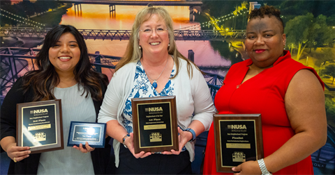 Three women holding award plaques