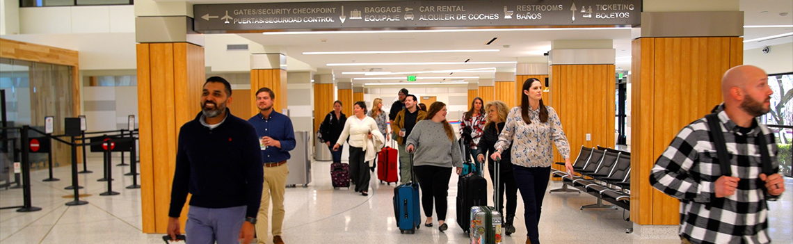 happy passengers walking through the airport with their luggage.