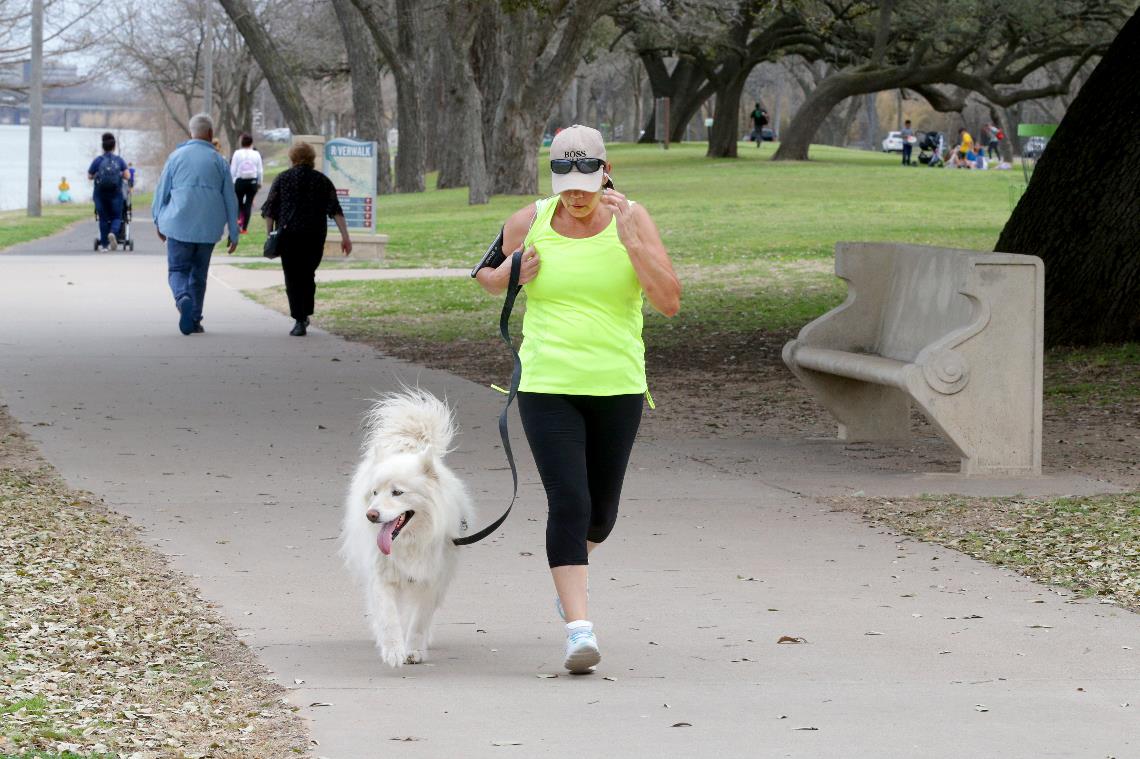 Photo of woman jogging along the Riverwalk with her dog.