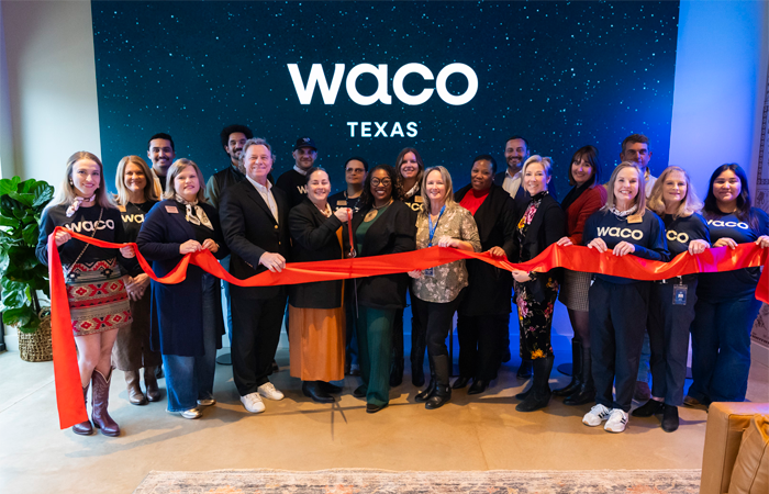 City officials, partners, and Welcome Center staff holding the red ribbon